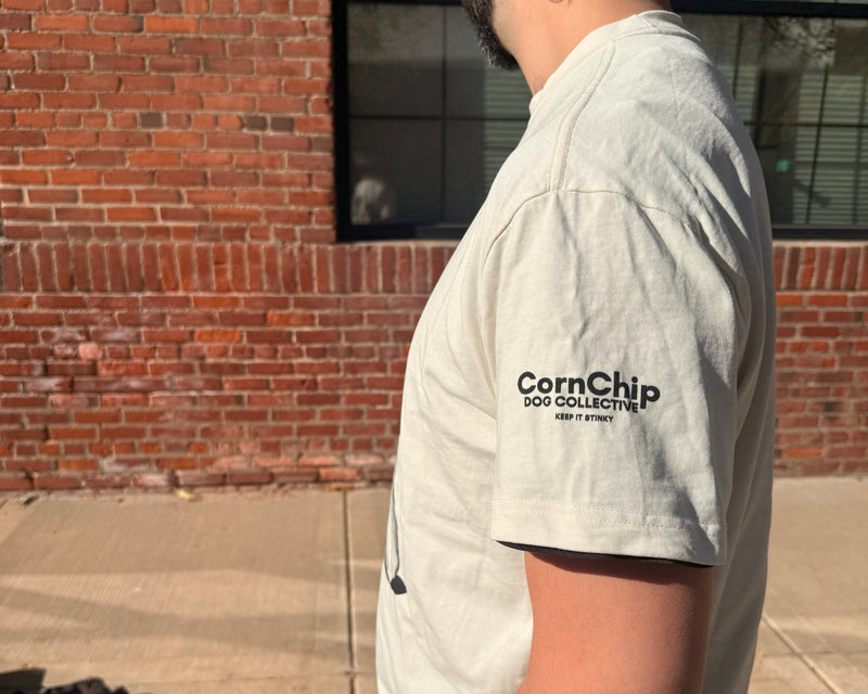 Person wearing a white t-shirt with 'Corn Chip' logo standing in front of a brick wall.