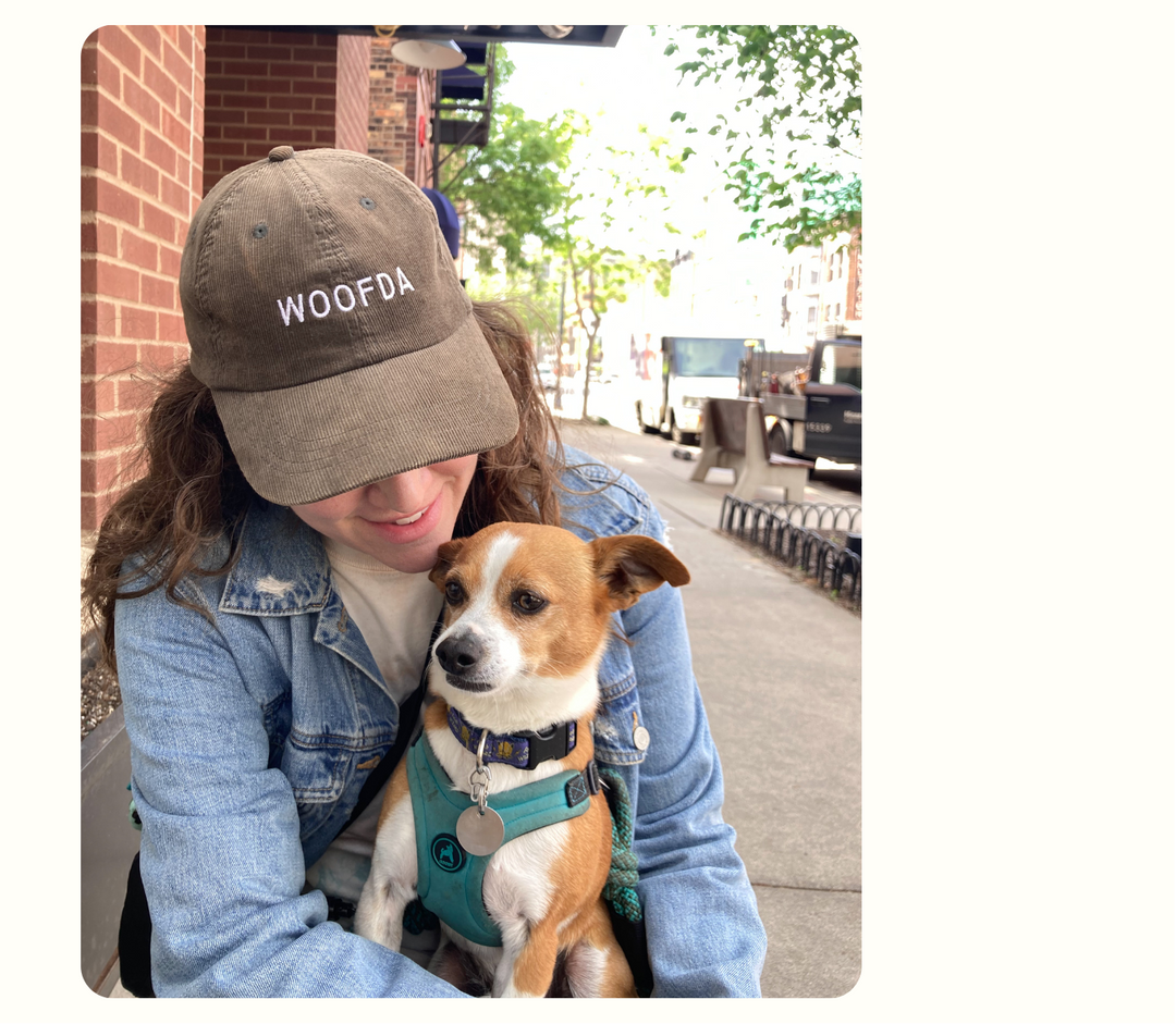 Person wearing a hat that says Woofda and a dog on her lap