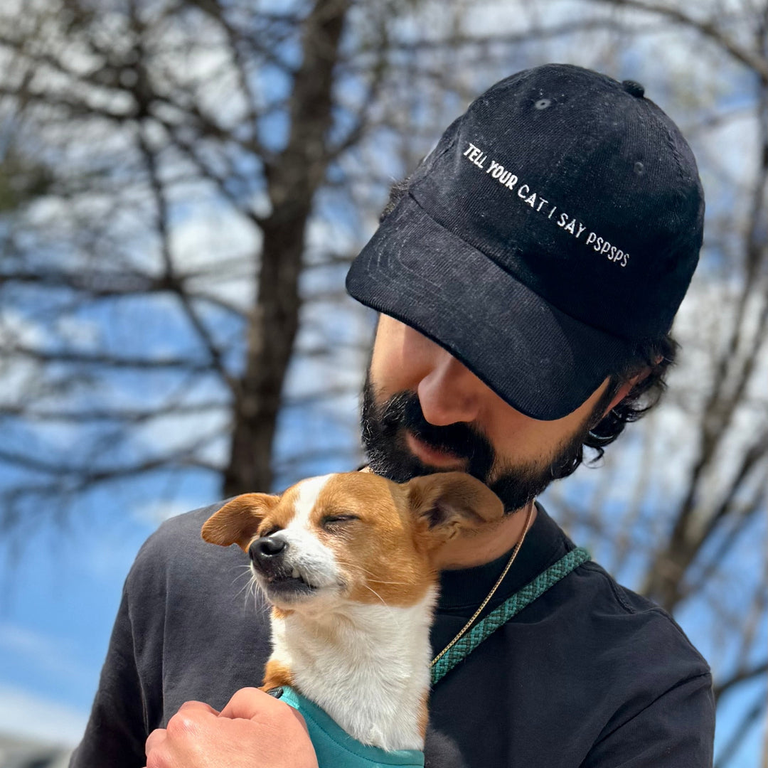 Man wearing a baseball hat holding a dog