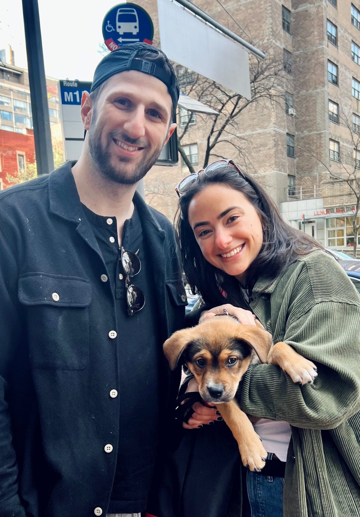 A man and woman holding a dog outside. 